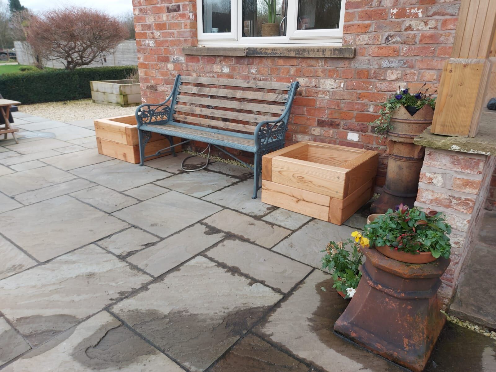 Oak planters on a stone patio beside a brick house